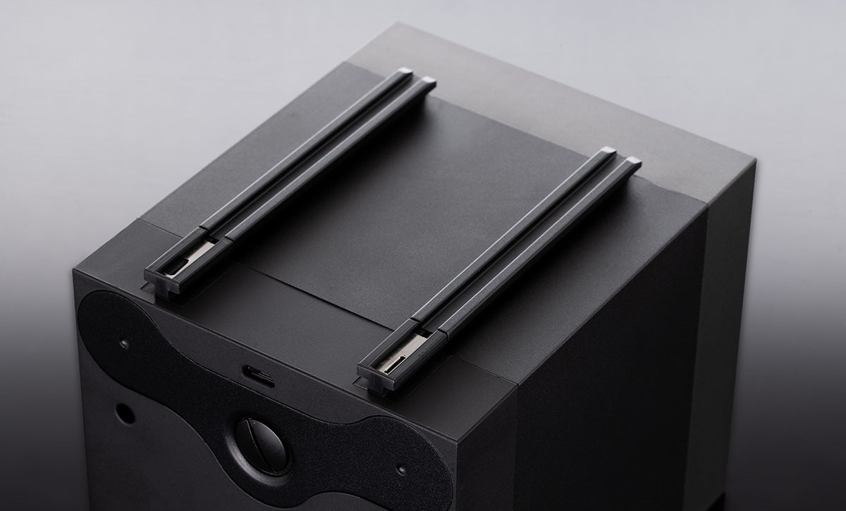 Das Bild zeigt die Unterseite des BOTTA Uhrenbewegers mit dem integrierten Schienensystem. Zwei stabile Metallschienen verlaufen parallel und ermöglichen die sichere Stapelung mehrerer Module. Das minimalistische schwarze Design unterstreicht die hochwertige Verarbeitung. Praktisch: Über das System lassen sich mehrere Uhrenbeweger mit nur einem USB-Kabel betreiben – ideal für Sammler, die eine modulare Uhrenbox kaufen oder bestellen möchten.