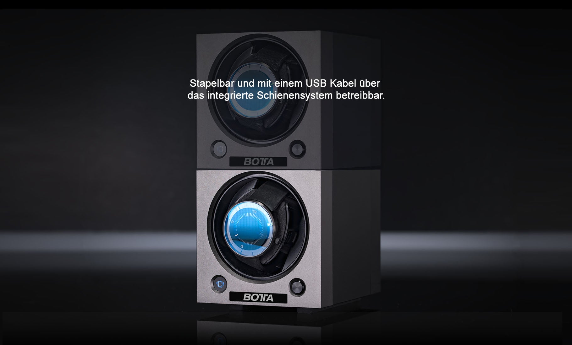 Zwei stapelbare BOTTA Uhrenbeweger im modernen, mattschwarzen Design, übereinander platziert und über das integrierte Schienensystem mit USB-Kabel betreibbar. Im Bild sind Designeruhren mit blauem Zifferblatt eingelegt, sichtbar durch die runde Frontöffnung. Diese innovative Uhrenbox ermöglicht platzsparende Aufbewahrung und gleichzeitigen Betrieb mehrerer Automatikuhren. Perfekt für Uhrensammler – jetzt kaufen oder bestellen.