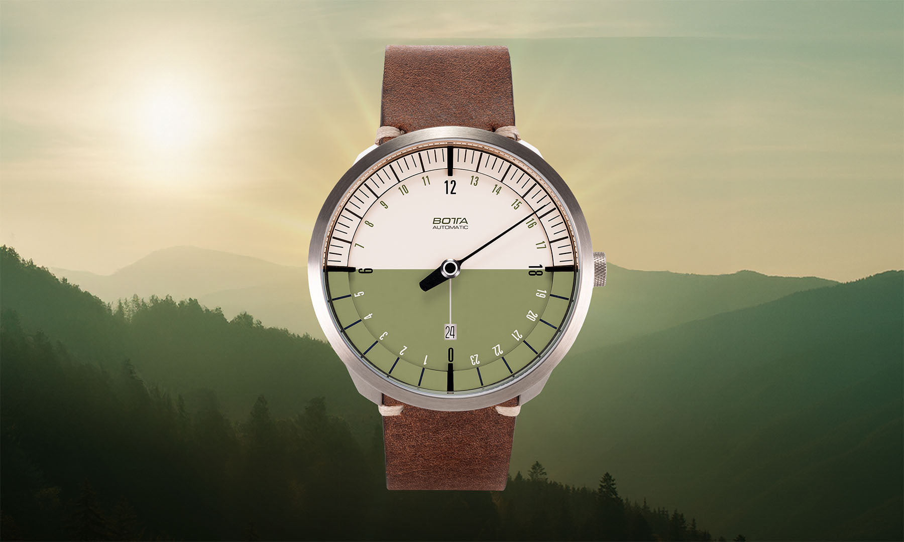 Vor einer sonnendurchfluteten Berglandschaft präsentiert sich die BOTTA UNO 24 Your Time in Olivgrün. Diese hochwertige Automatikuhr ist eine 24-Stunden Uhr mit einem Zeiger und zeigt den gesamten Tagesverlauf sonnen¬synchron und logisch an. Das zweifarbige Zifferblatt in Hell und Dunkel symbolisiert Tag und Nacht, das braune Lederband ergänzt das natürliche Design. Eine Einzeiger Automatikuhr, die Ruhe und Klarheit vermittelt. Jetzt kaufen oder bestellen.