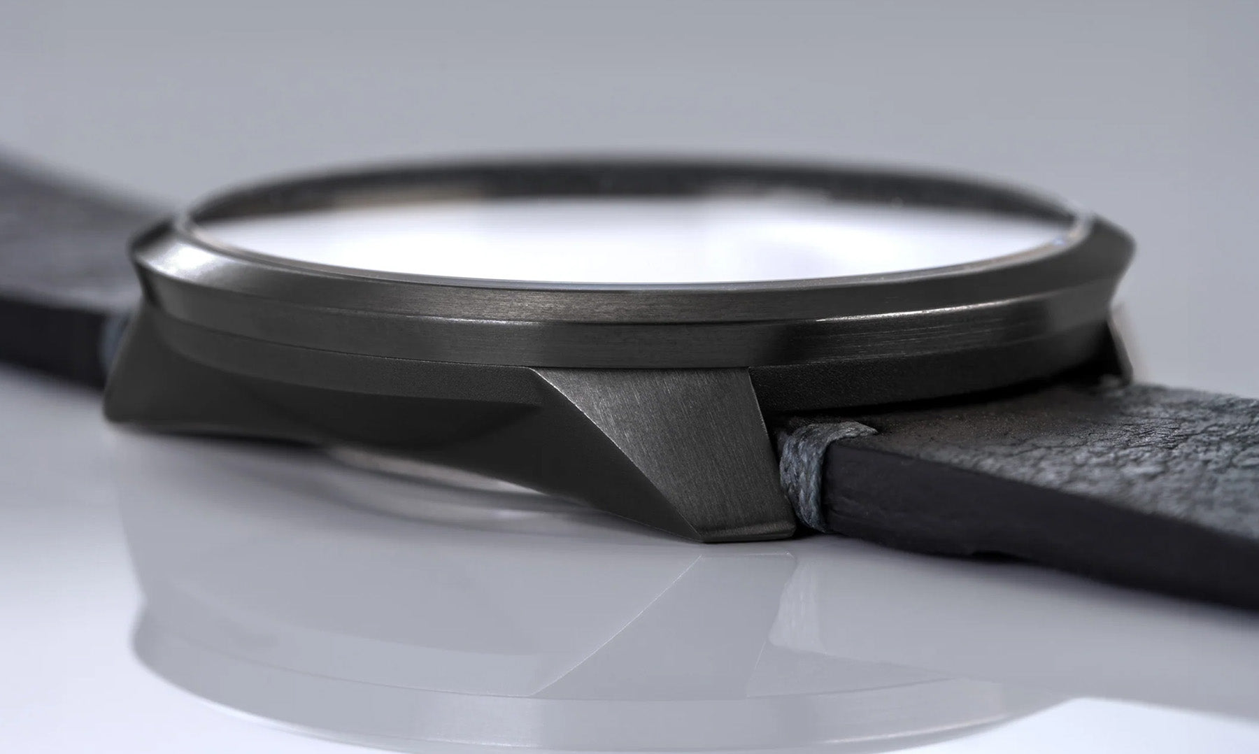 Detailaufnahme des Gehäuses einer BOTTA Automatikuhr im All-Black-Design. Das kantige Tri-Titan-Gehäuse mit matt gebürsteter Oberfläche zeigt die präzise Verarbeitung und hochwertige Materialqualität. Diese 24-Stunden Uhr mit einem Zeiger ist eine exklusive Einzeiger Automatikuhr, die technisches Können und minimalistisches Design vereint. Eine hochwertige Automatikuhr Made in Germany. Jetzt kaufen oder bestellen.