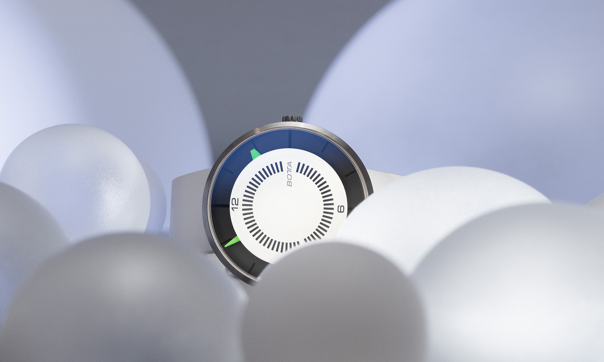 Die BOTTA CLAVIUS Cumulus Automatikuhr präsentiert sich hier in einer atmosphärischen Szene, umgeben von weißen Kugeln, die Leichtigkeit und Wolkenassoziationen hervorrufen. Das weiße Zifferblatt mit markanten schwarzen Skalenringen wird durch leuchtend grüne Indikationen betont – eine minimalistische Automatikuhr, die Zeit auf das Wesentliche reduziert. Handgefertigt in Deutschland, aus Titan, ausgezeichnet als Designuhr. Diese exklusive Armbanduhr jetzt entdecken, kaufen und bestellen.
