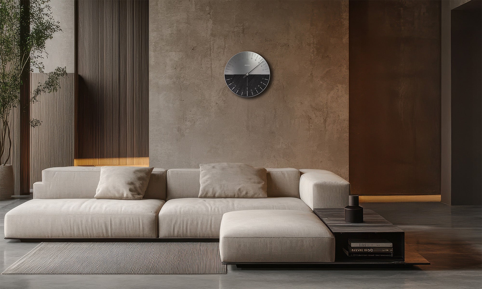 Modern eingerichtetes Wohnzimmer mit heller Couch und puristischem Interieur. An der Wand hängt die UNO 24 Slate Wanduhr von BOTTA, eine exklusive 24 Stunden Designwanduhr mit einem Zeiger. Das Zifferblatt kombiniert gebürsteten Edelstahl mit natürlichem Schiefer und verleiht dem Raum eine edle, architektonische Note. Diese Wanduhr im Schieferdesign ist ein Statement moderner Zeitgestaltung – jetzt die UNO 24 Slate Wanduhr kaufen oder bestellen.