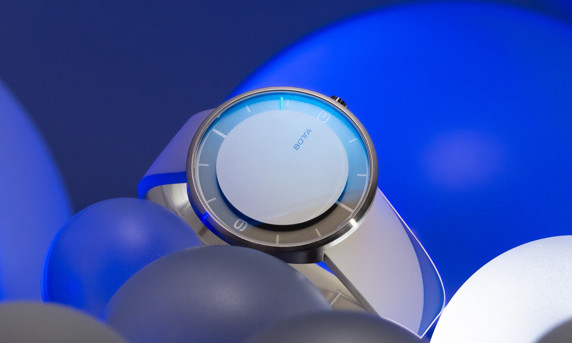Die schlanke NOVA Automatik von BOTTA erscheint hier in einer künstlerischen Inszenierung mit blauen Kugeln und Lichteffekten. Als Einzeigeruhr konzentriert sie sich auf das Wesentliche: ein klares, aufgeräumtes Zifferblatt mit nur einem diskreten Stundenindikator. Das Titangehäuse und das Lederarmband unterstreichen den hochwertigen Charakter dieser Designuhr. Eine besondere Armbanduhr, die Minimalismus neu definiert und als exklusive Automatikuhr zum Kaufen oder Bestellen erhältlich ist.