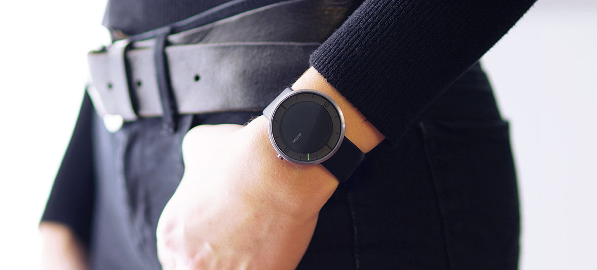 Die BOTTA NOVA Quarzuhr in Schwarz, getragen am Handgelenk, verkörpert minimalistisches Design und klare Eleganz. Das schwarze Zifferblatt mit nur einem grünen Zeiger unterstreicht die Idee der Einzeigeruhr – Zeit bewusst reduziert erleben. Das matte Gehäuse, das dezente Lederarmband und die hochwertige Verarbeitung machen diese Designuhr zu einer stilvollen Armbanduhr für Puristen. Ideal für alle, die eine außergewöhnliche Uhr mit einem Zeiger kaufen oder bestellen möchten.