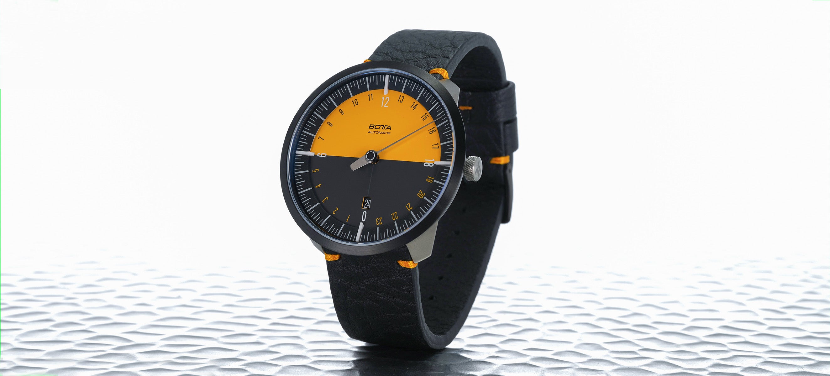 Das Bild zeigt die BOTTA UNO 24 Jubiläumsedition, eine limitierte Automatikuhr mit markantem orange-schwarzem Zifferblatt im 24-Stunden-Einzeigerprinzip. Das Tri-Titan-Gehäuse, das präzise Sellita SW330 Automatikwerk und das doppelt gewölbte Saphirglas unterstreichen die Hochwertigkeit. Diese Designuhr ist eine außergewöhnliche Armbanduhr für Individualisten. Wer eine besondere Uhr mit einem Zeiger kaufen oder bestellen möchte, findet hier ein exklusives Sammlerstück.