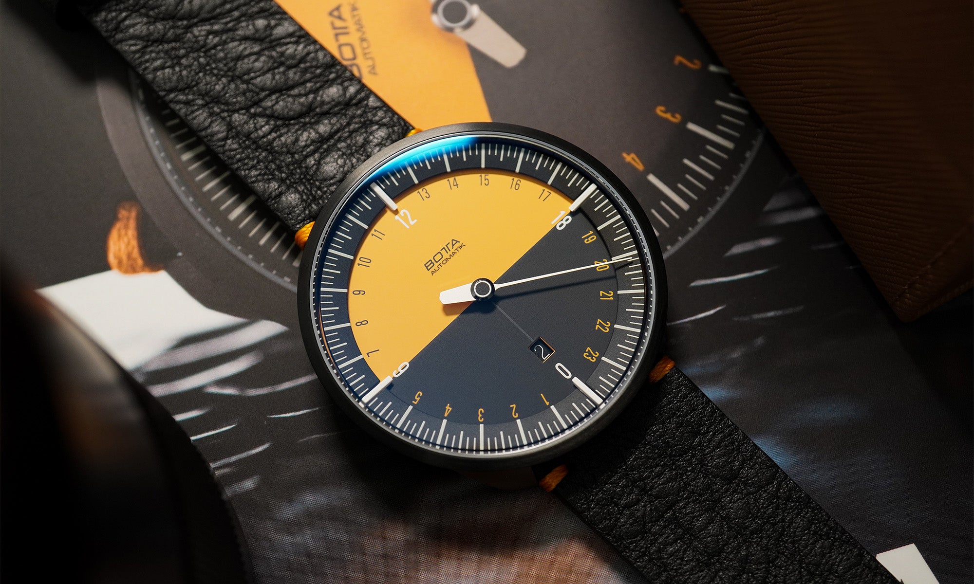 Abgebildet ist die UNO 24 Jubiläumsedition von BOTTA Design – eine Einzeigeruhr mit auffälligem Zifferblatt in Orange und Schwarz. Diese Automatikuhr zeigt den gesamten Tagesverlauf im 24h-Format mit nur einem Zeiger und kombiniert so Natürlichkeit und Logik in der Zeitdarstellung. Mit Tri-Titan-Gehäuse, Saphirglas und Sellita SW330 Automatikwerk ist diese Designuhr hochwertig und präzise gefertigt.